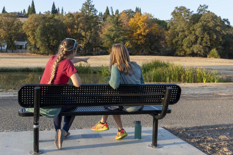 Two people sit on a bench in the Sunset Whitney Recreation Area that was donated by members of the public .