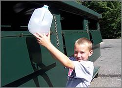 photo of boy dropping recyclable bottle in bin