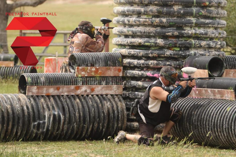 Two people play paintball with Predator Paintball equipment at a nearby field.