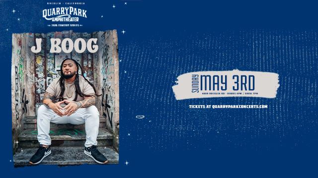 Promotional poster for the Quarry Park Amphitheater 2026 Concert Series featuring reggae artist J Boog. The image shows J Boog seated on concrete steps in front of a graffiti covered wall, wearing a tan shirt, white pants, black sneakers, and a gold chain, with long dark dreadlocks and tattoos on both arms. Text at the top reads Rocklin California Quarry Park Amphitheater 2026 Concert Series. Large text above the artist reads J Boog. At the bottom, text reads Sunday May 3rd, 4000 Rocklin Road, Doors 6pm, Show 7pm. Tickets at QuarryParkConcerts.com.