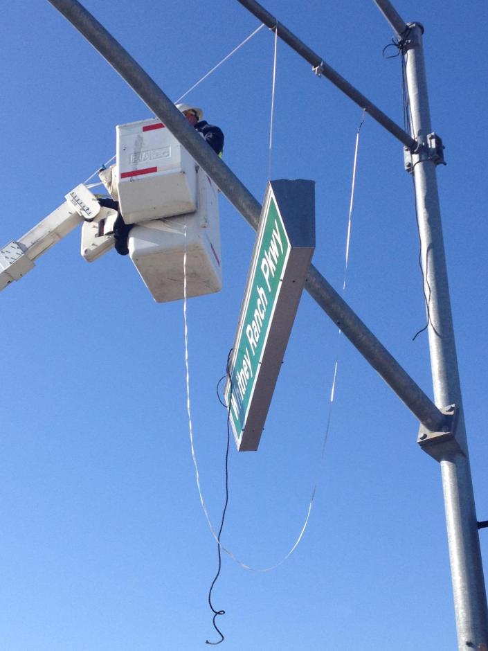 Member of Rocklin's Traffic Division works on a street sign from a crane bucket.